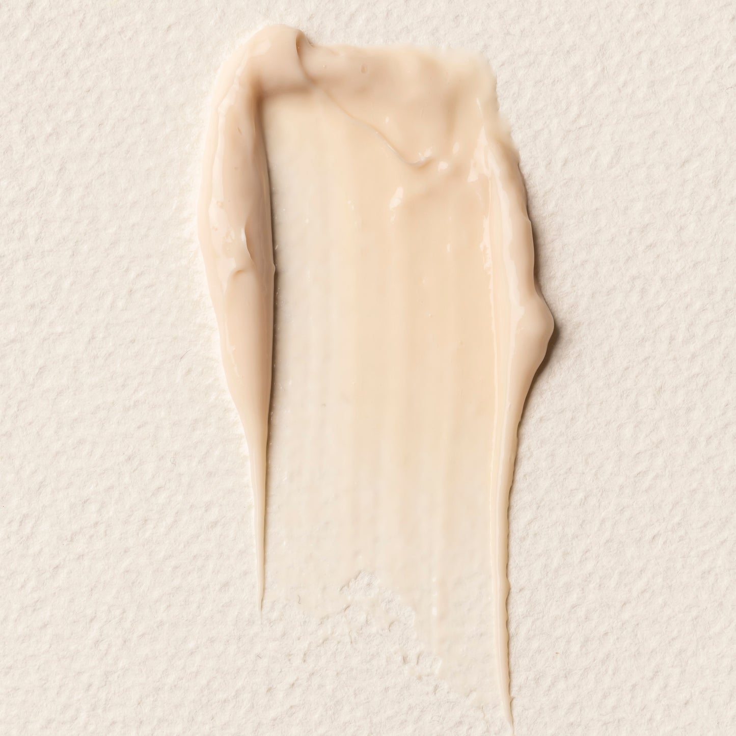 Beige cream swatch on a textured beige background. TRONQUE Exfoliating Refining Serum