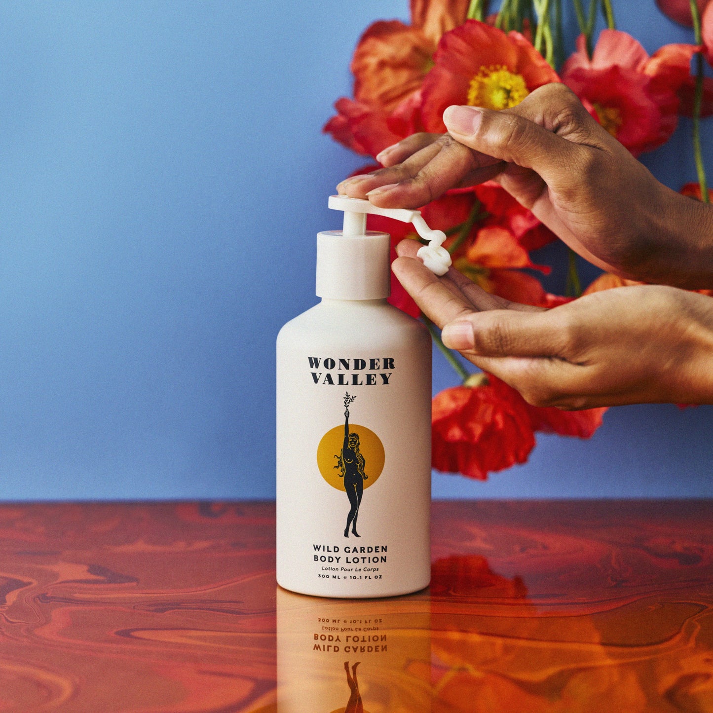 Person using Wonder Valley body lotion with flowers in the background. WONDER VALLEY Wild Garden Body Lotion