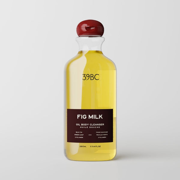 A clear bottle of 39BC Fig Milk Oil Body Cleanser filled with yellow oil, featuring a dark brown label and a glossy red cap, set against a light gray background.