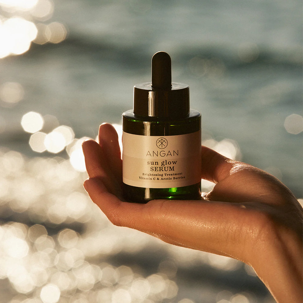 ANGAN Sun Glow Vitamin-C Serum in a glass bottle with a pump, featuring 15% vitamin C, Arctic berries, and Icelandic botanicals to brighten and even out skin tone.