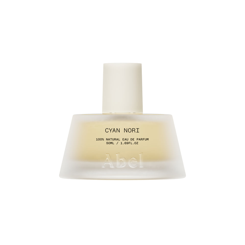 A frosted glass perfume bottle with a matte white cap, containing a pale yellow liquid. The label reads 'CYAN NORI 100% NATURAL EAU DE PARFUM' and features the brand name 'Abel' embossed near the bottom.