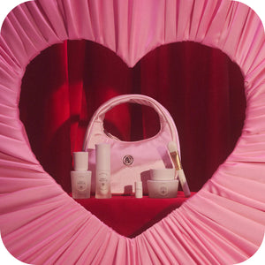 Pink cosmetic bag with skincare products inside, framed by a heart-shaped pink border.