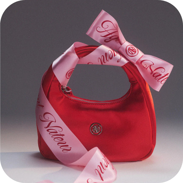 Red handbag with a pink ribbon on a gray background