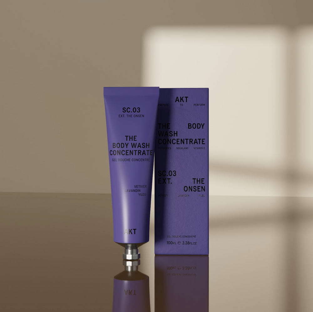 A lavender purple squeeze tube of AKT London The Body Wash Concentrate (SC.03) with a silver metal cap, centered on a clean off-white background.