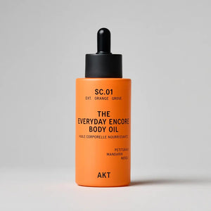 Orange bottle of 'The Everyday Encore Body Oil' with black cap on a light gray background
