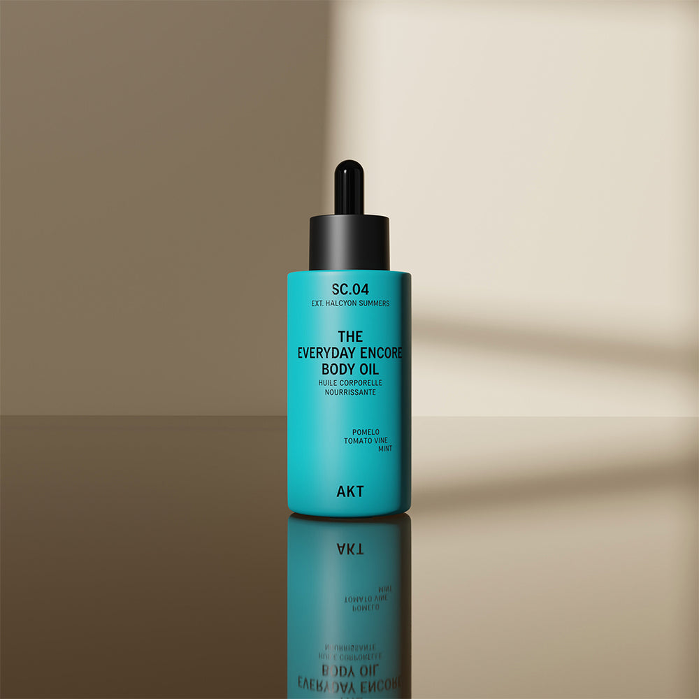 A turquoise bottle of AKT London The Everyday Encore Body Oil with a black dropper cap, set against a plain white background.