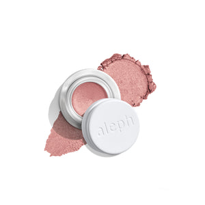 A small open jar of ALEPH blush with a white lid resting beside it, showing a shimmery dusty rose pink cream product with matching powder smears on a clean white background.
