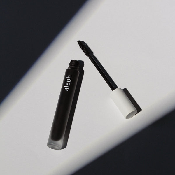 ALEPH Lift / Lengthen Mascara with open cap on a reflective surface