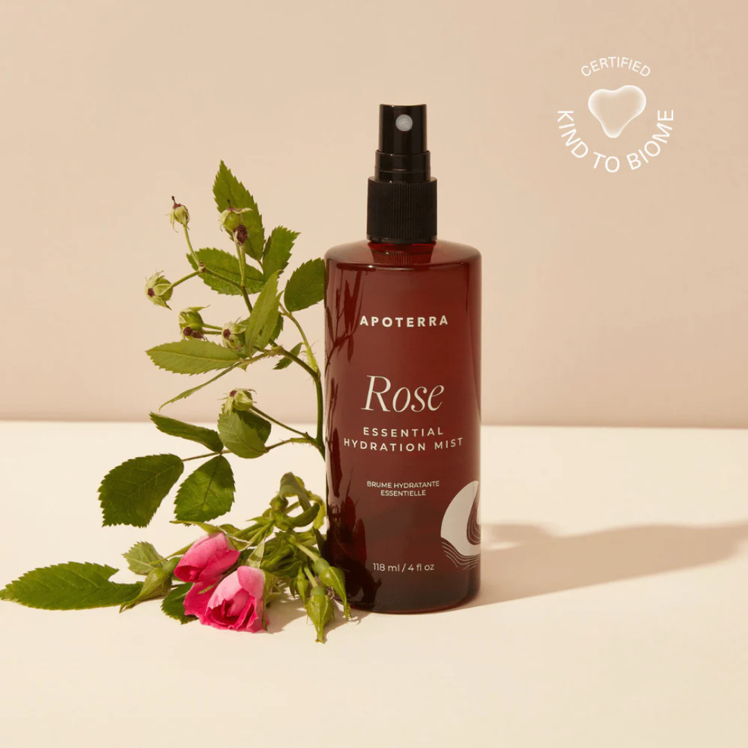 Apoterra Rose Essential Hydration Mist bottle with a sprayer on a beige background, accompanied by a rose.