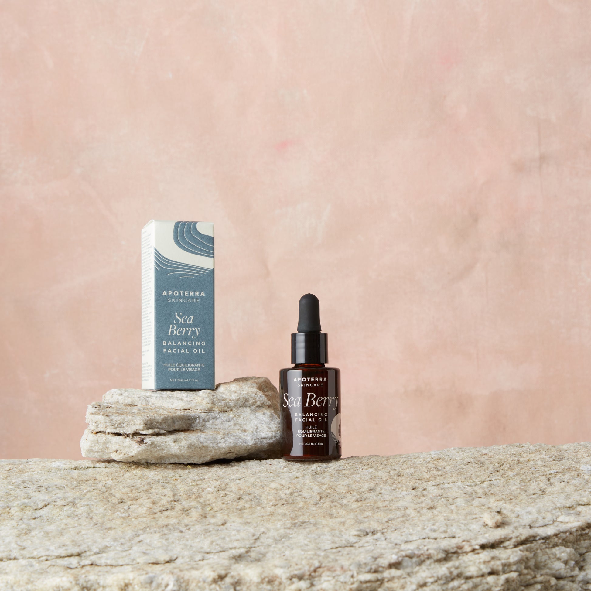 Apoterra Sea Berry facial oil bottle and packaging on a stone surface with a pink background
