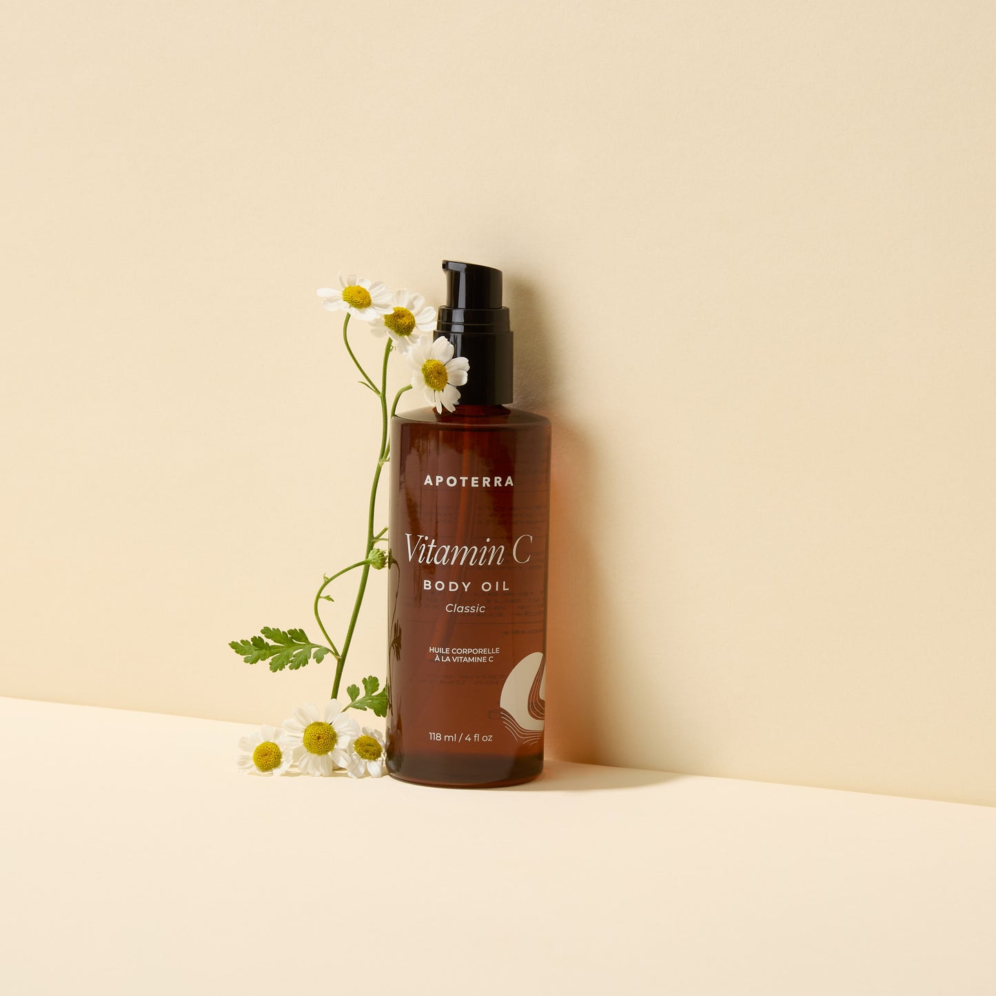 Brown bottle of Apoterra Vitamin C Body Oil with flowers on a beige background