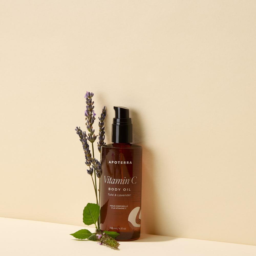 Apoterra Vitamin C Body Oil Tulsi and Lavender bottle with natural ingredients including tulsi leaves, lavender flowers, and orange peel.