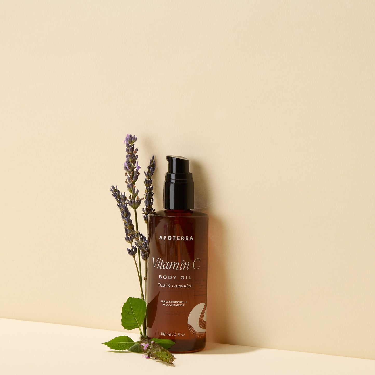 Brown bottle of Apoterra Vitamin C Body Oil with lavender sprigs on a beige background