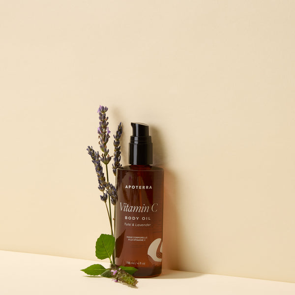 Brown bottle of Apoterra Vitamin C Body Oil with lavender sprigs on a beige background