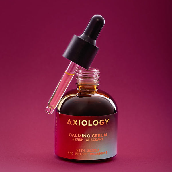 Axiology calming serum bottle with dropper on a purple background