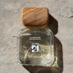 Clear glass perfume bottle with wooden cap on a stone surface