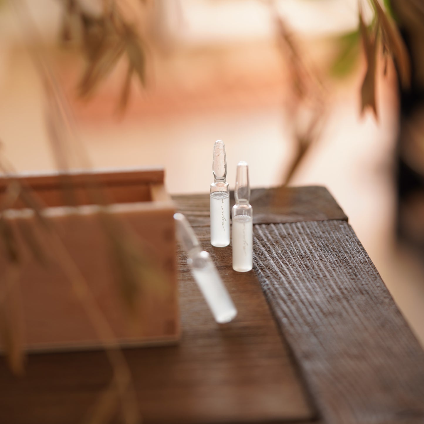 Two clear glass ampoules on a wooden surface with a blurred background