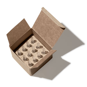 Open cardboard box containing small skincare ampoules from Ayuna on a white background