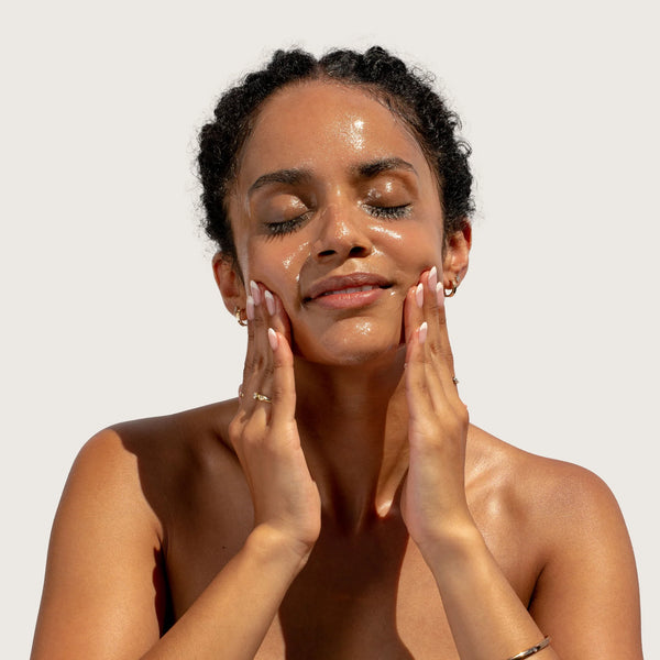 Woman applying BLOOMEFFECTS Royal Tulip Cleansing Jelly to her face against a plain background