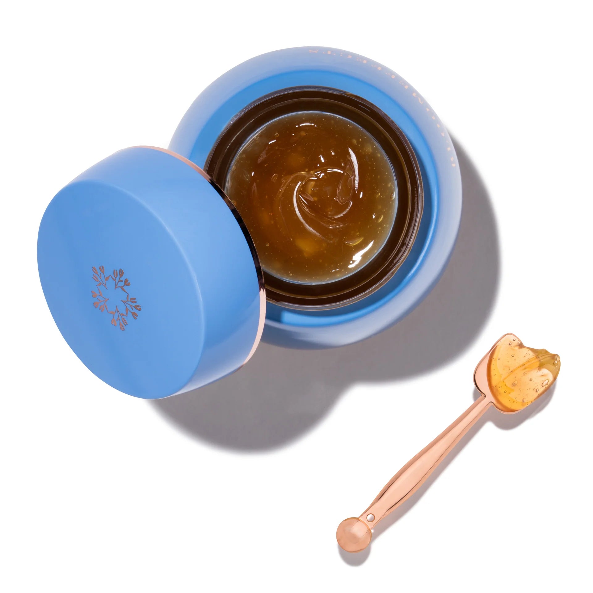 Open blue jar of BLOOMEFFECTS Royal Tulip Moisturizing Nectar with a spoonful of the jelly like balm on a white background