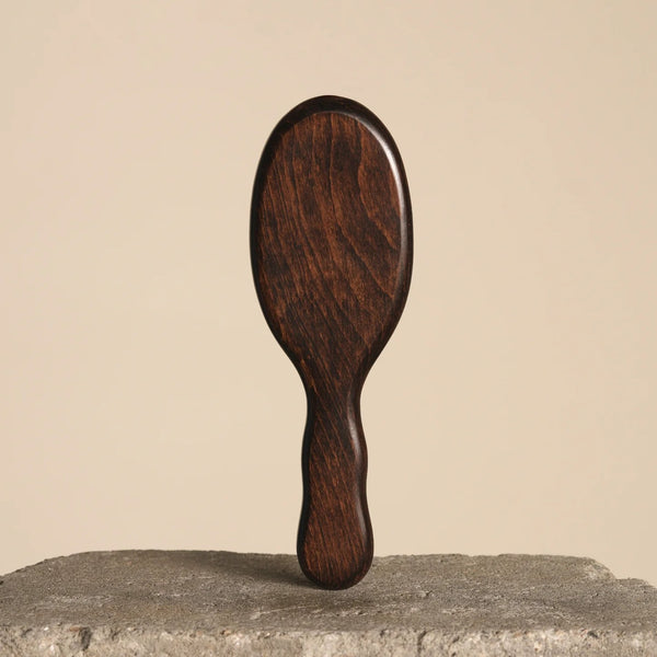 Wooden hairbrush on a textured surface with a beige background