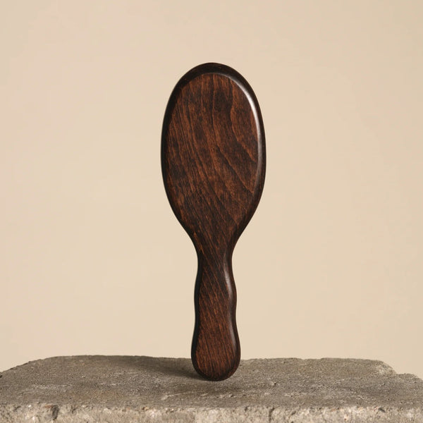 Wooden hair brush on a textured surface with a beige background