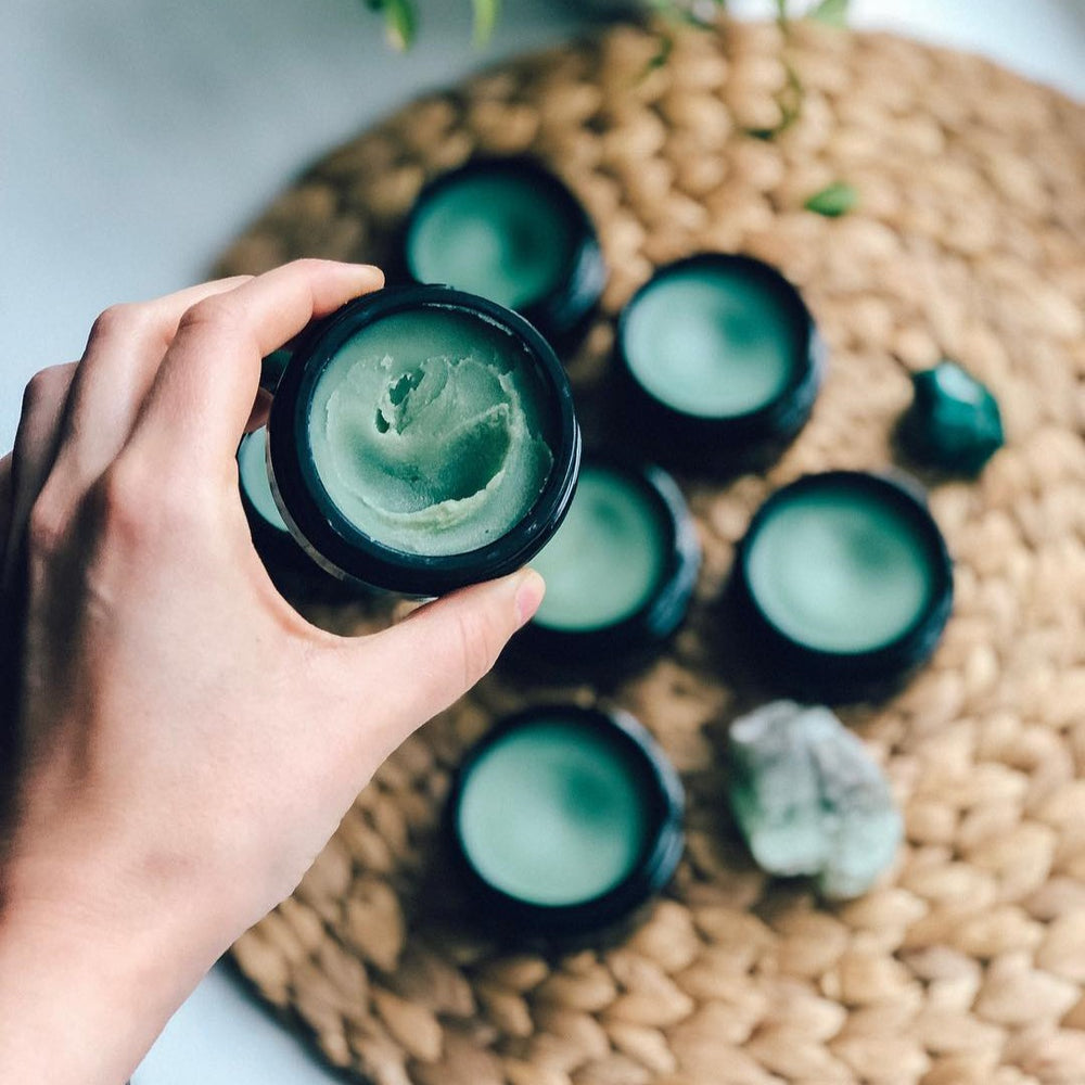 By Achilles Beauty Balm in jar, showcasing its rich, green, botanical formula designed to hydrate and nourish the skin.