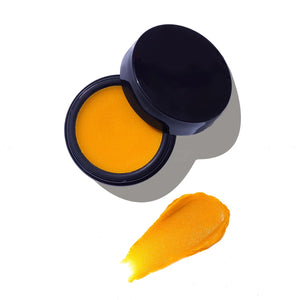 Open black glass jar of orange Solace face balm from By Achilles with a black lid on a white background