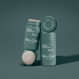 Two green deodorant sticks with 'Cleo + Coco' branding on a dark green background