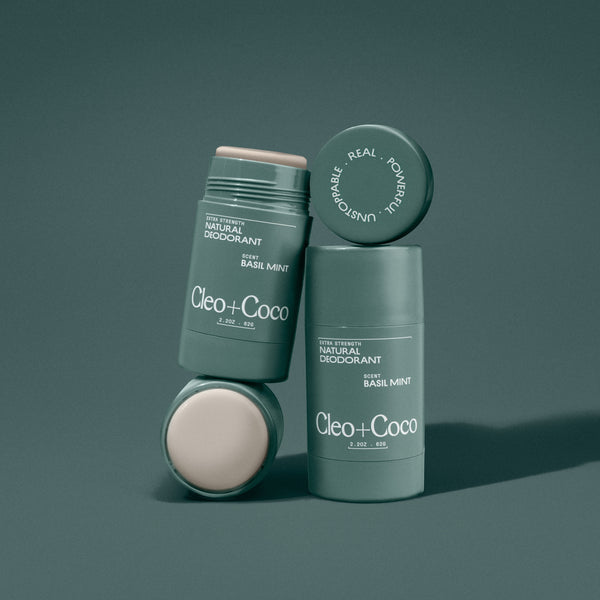 Two green deodorant sticks with 'Cleo + Coco' branding on a dark green background