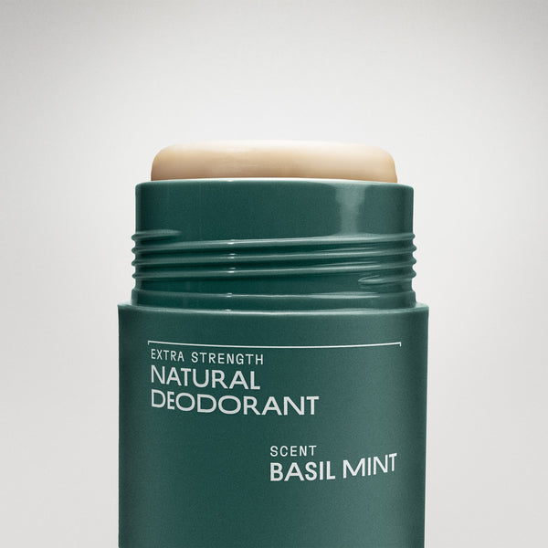 Green deodorant stick with 'Basil Mint' scent on a light gray background