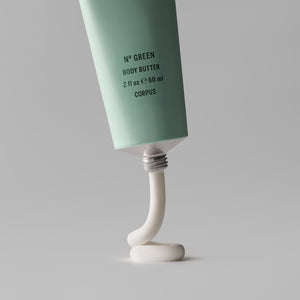 Tube of green body butter with white cream oozing out on a gray background. CORPUS Body Butter Nº Green Mini