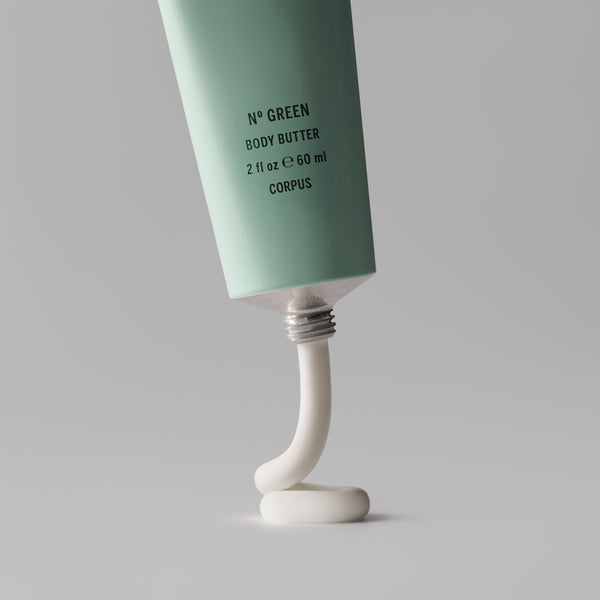 Tube of green body butter with white cream oozing out on a gray background. CORPUS Body Butter Nº Green Mini