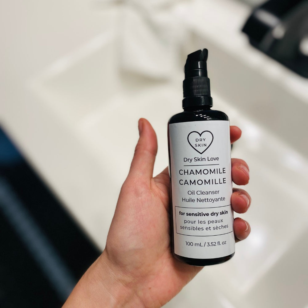 Dry Skin Love Chamomile Oil Cleanser for dry sensitive skin, featuring organic blue chamomile CO2 extract and plant oils. In black glass bottle with white label and black pump