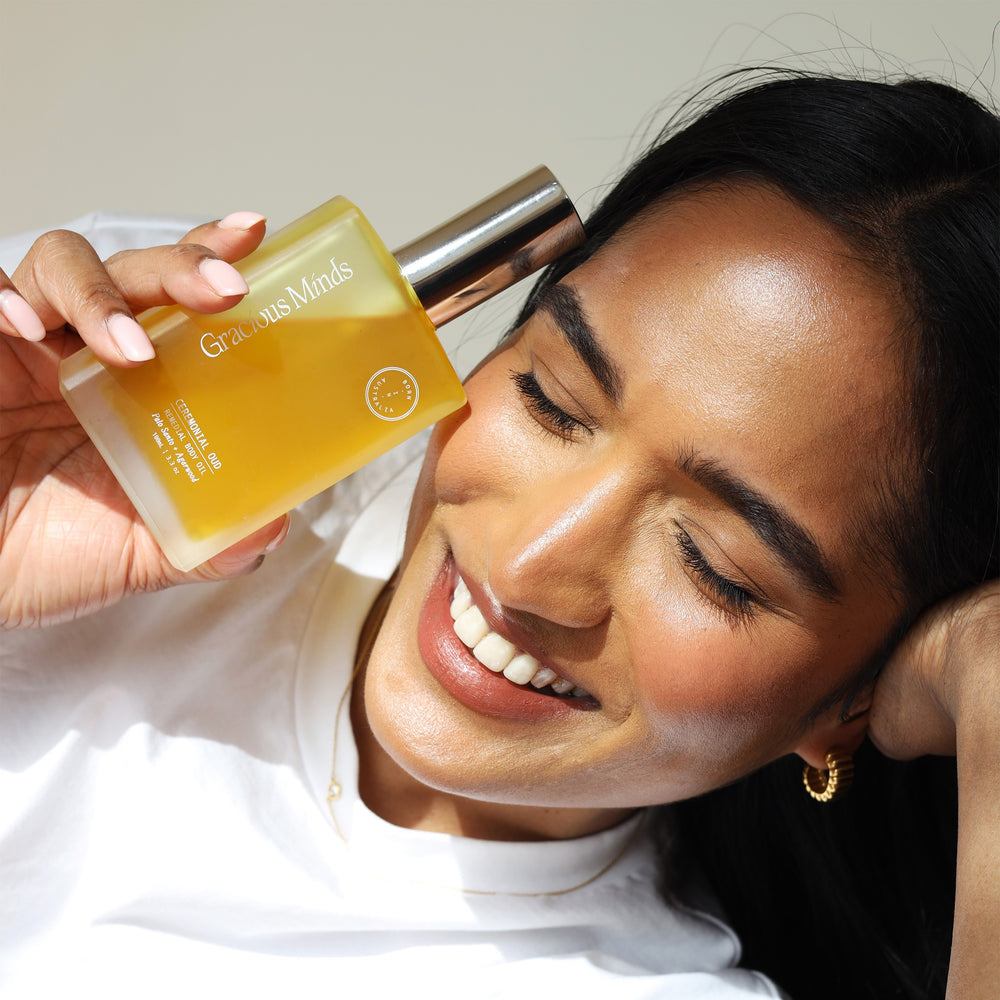 Gracious Minds Ceremonial Oud Body Oil bottle with a wooden background, highlighting its luxurious design and ingredients.