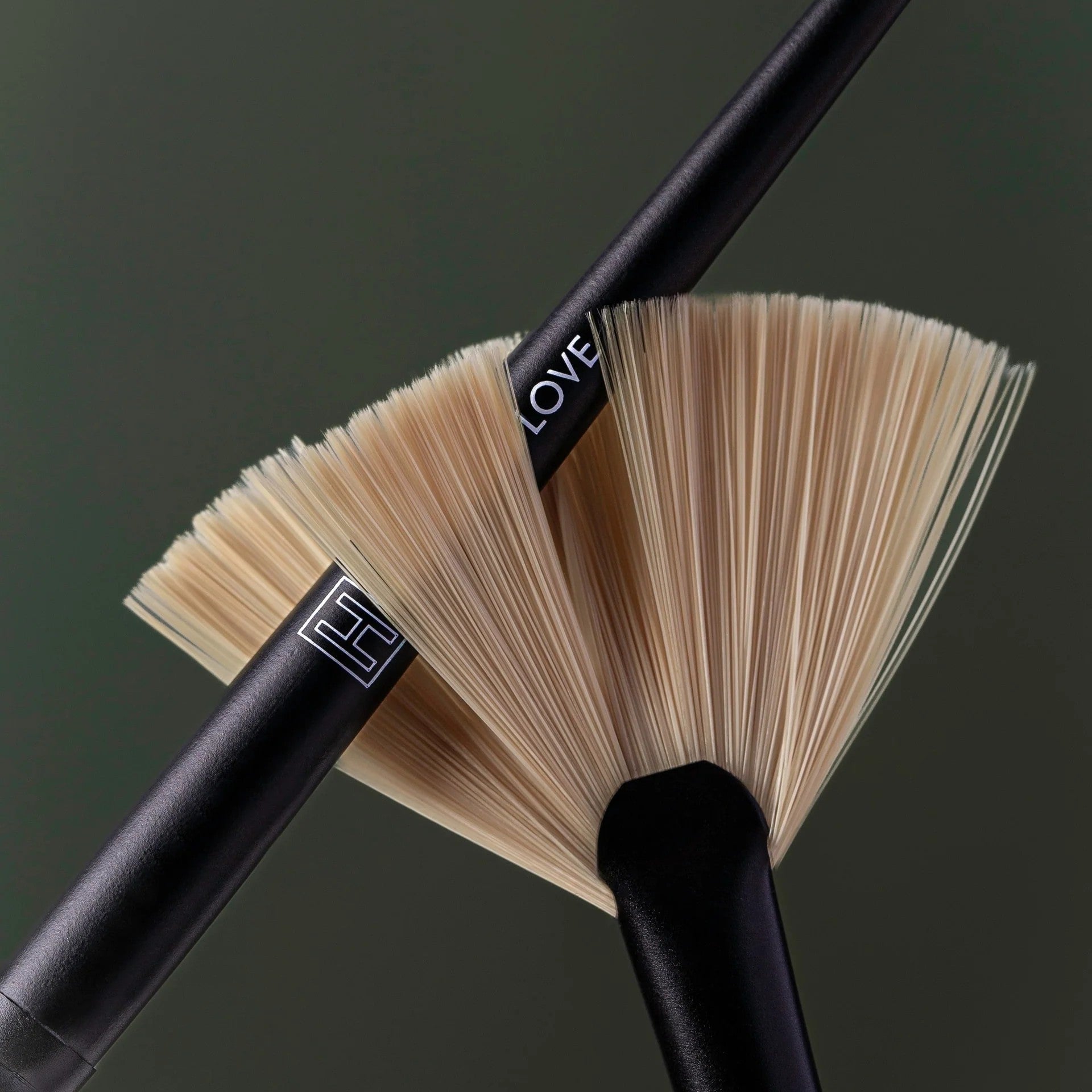 Makeup brushes with black handles and fan-shaped bristles on a dark background