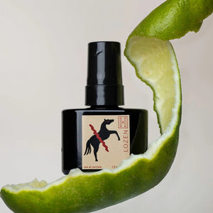 Black perfume bottle with a label on a sliced lime background
