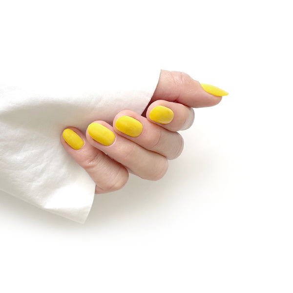 Hand with yellow nail polish on a white background