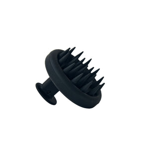 A soft silicone HINU Scalp Massager with rounded bristles, shown resting on a neutral surface—designed to gently exfoliate and massage the scalp for healthier, refreshed hair.