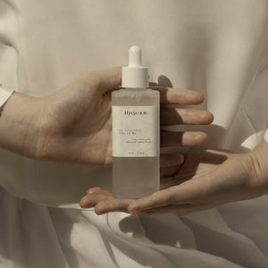 Person holding a bottle of Hyeja skincare product against a neutral background