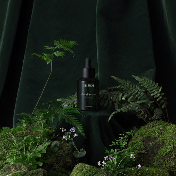 Dark green bottle with dropper labeled 'INBLUEM' on a dark background with greenery