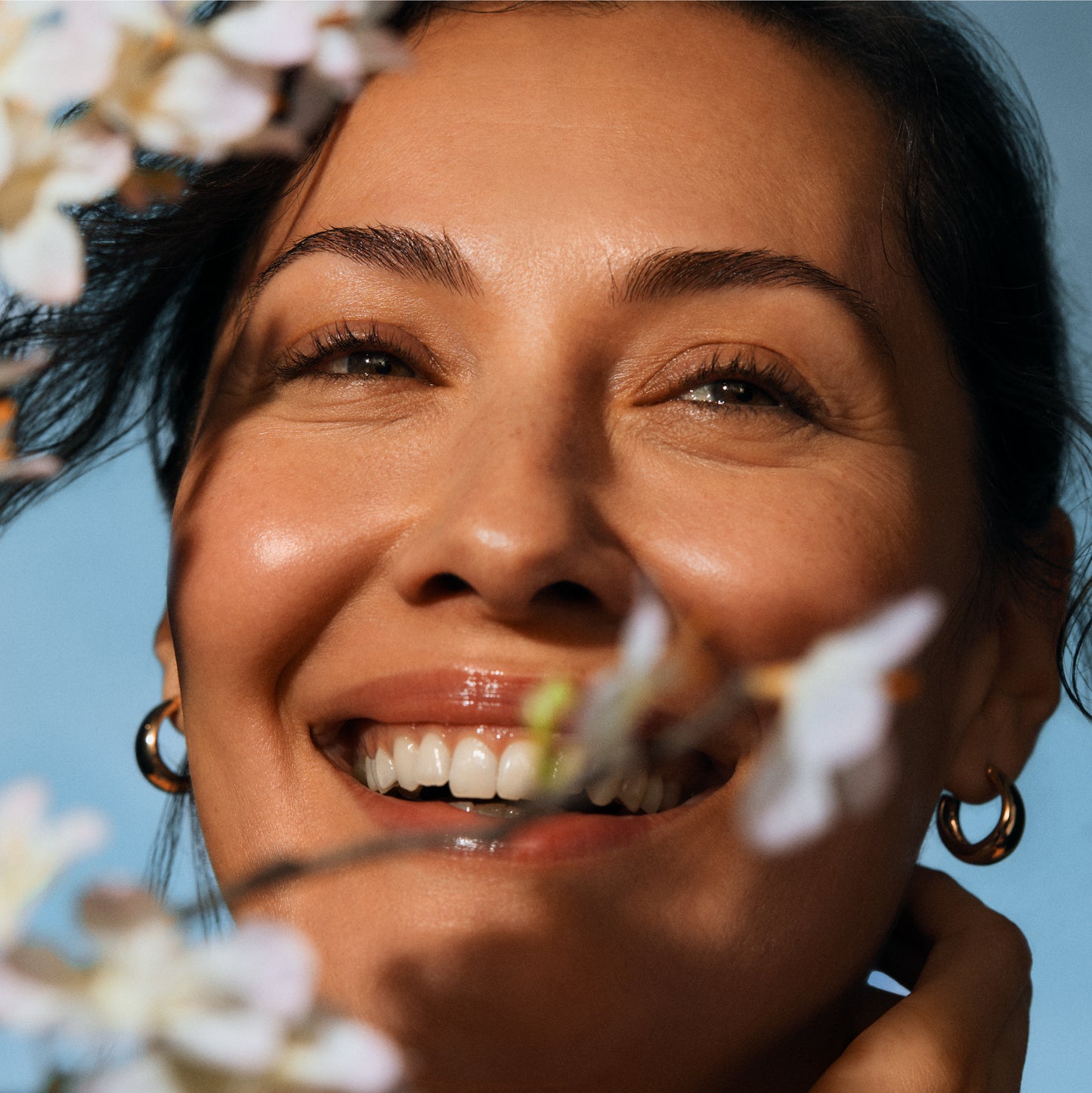 Woman smiling with a clear blue sky background. IRENE FORTE SKINCARE Almond Cleansing Milk