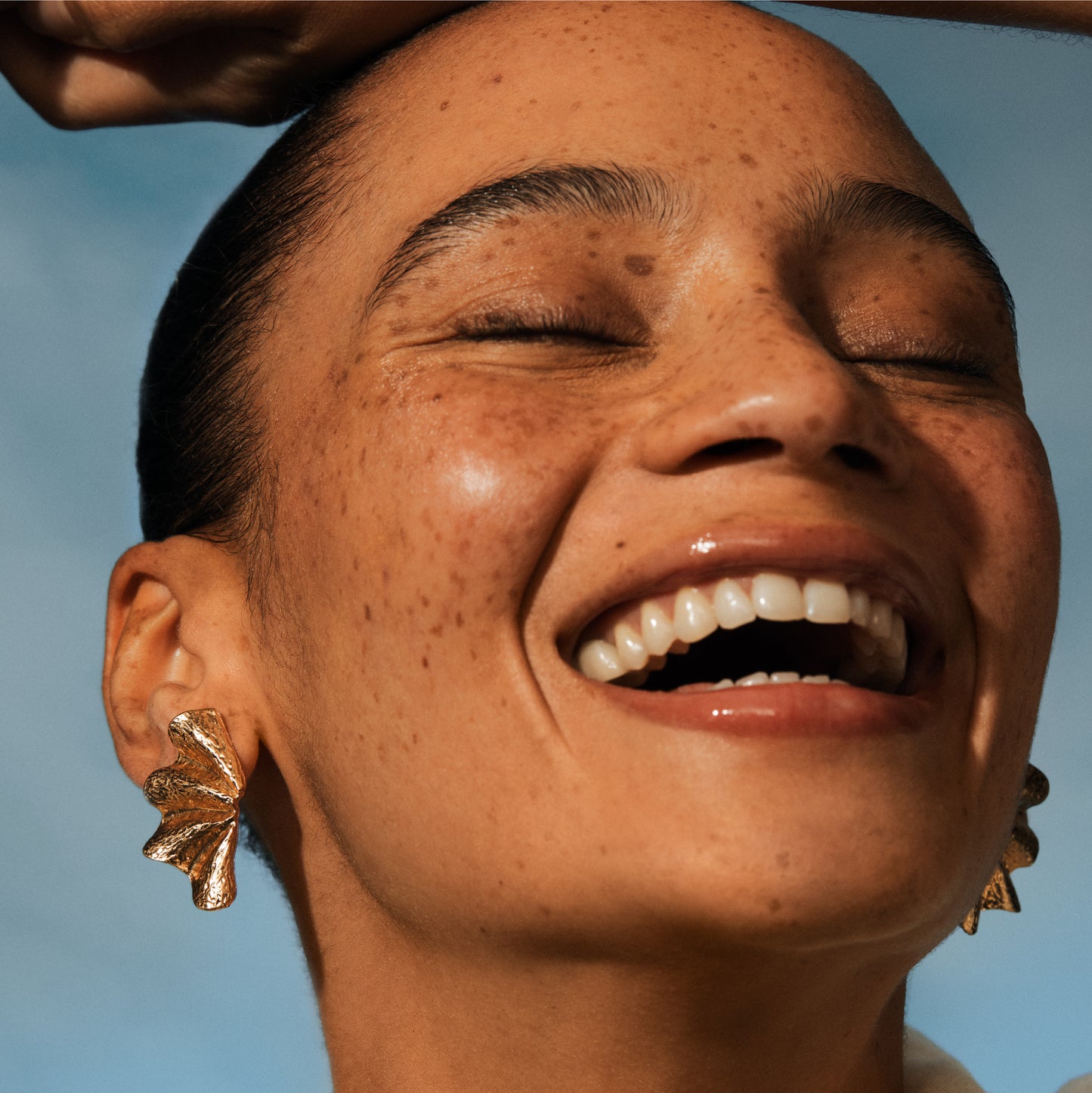 Close-up of a woman laughing with a clear blue sky background. IRENE FORTE SKINCARE Lavender Foam Cleanser