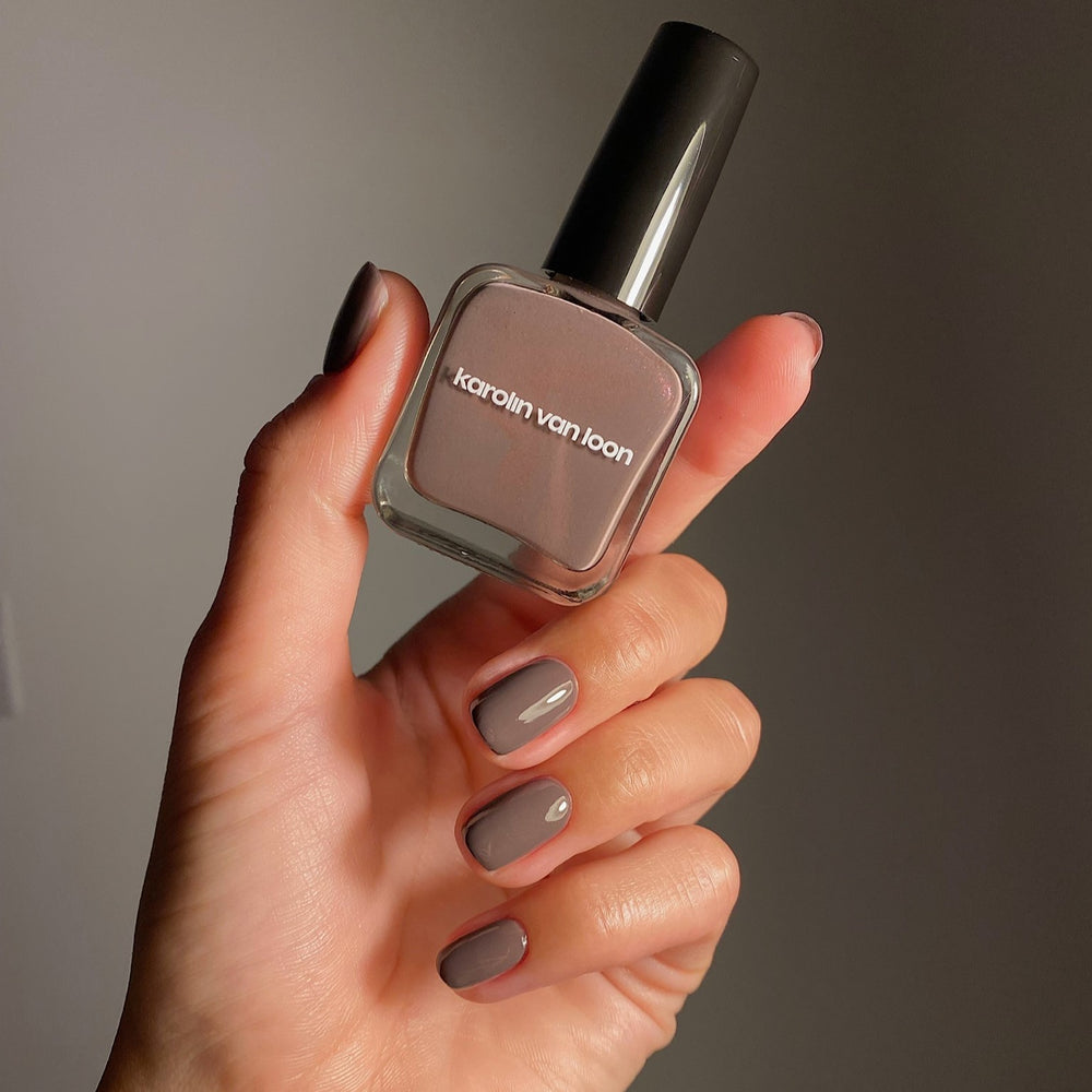 A bottle of Karolin Van Loon nail polish in shade 47 Taupe Lustré, featuring a classic taupe color with a subtle shimmer that catches the light, reminiscent of agate and diamond jewelry.