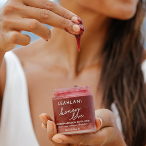 Person applying a red exfoliant to their skin with a jar of Leahlani honey love exfoliant in the foreground. LEAHLANI SKINCARE Honey Love Exfoliator ALWAYS SHOW