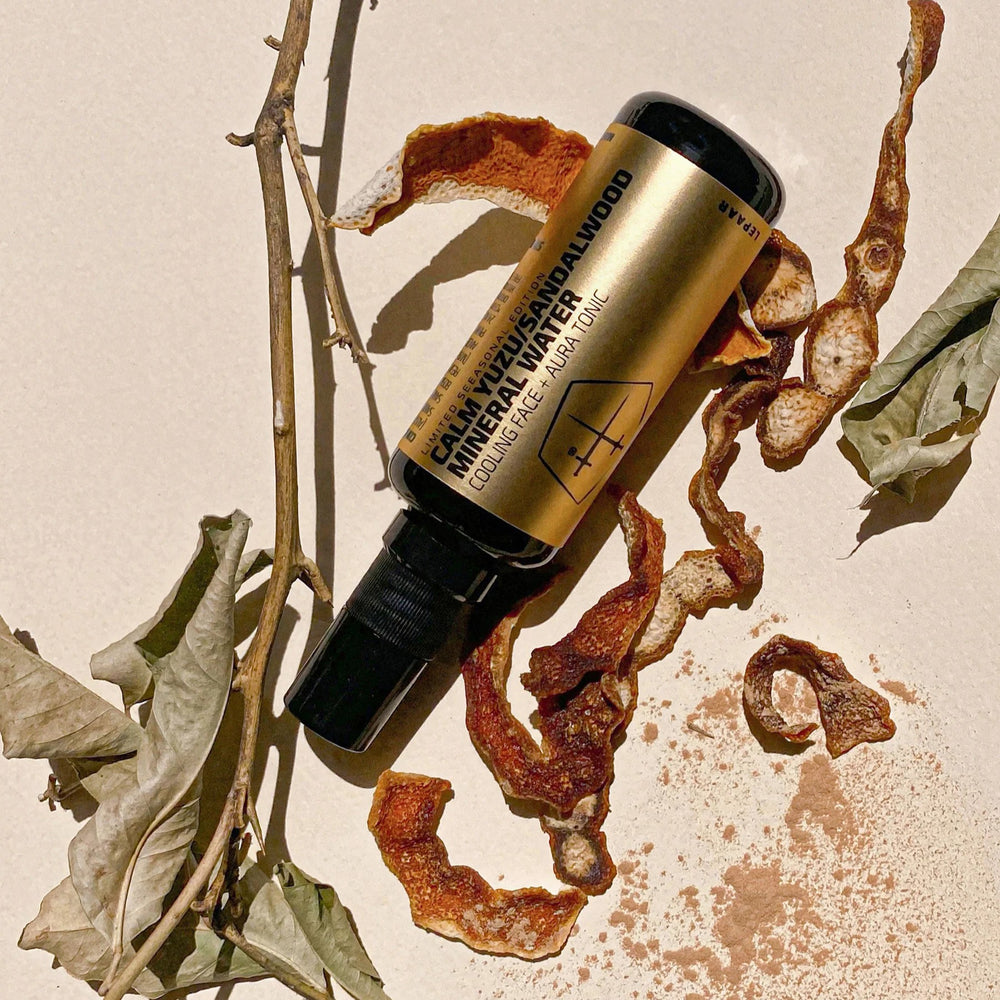 Balck glass ottle with a silver label on a white background. LEPAAR Calm Yuzu Sandalwood Mineral Water / Cooling Face + Aura Tonic