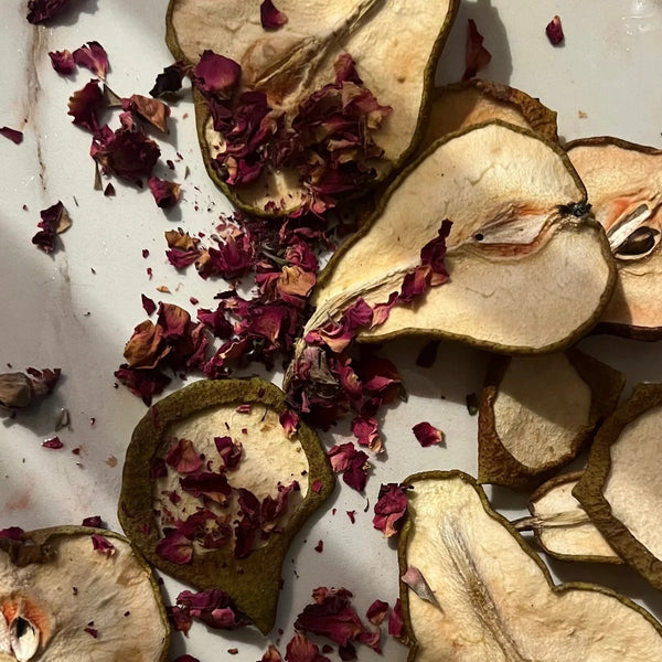 Dried pear slices with red rose petals on a white surface. LEPAAR Harmony Rose Serum / Face + Neck Oil