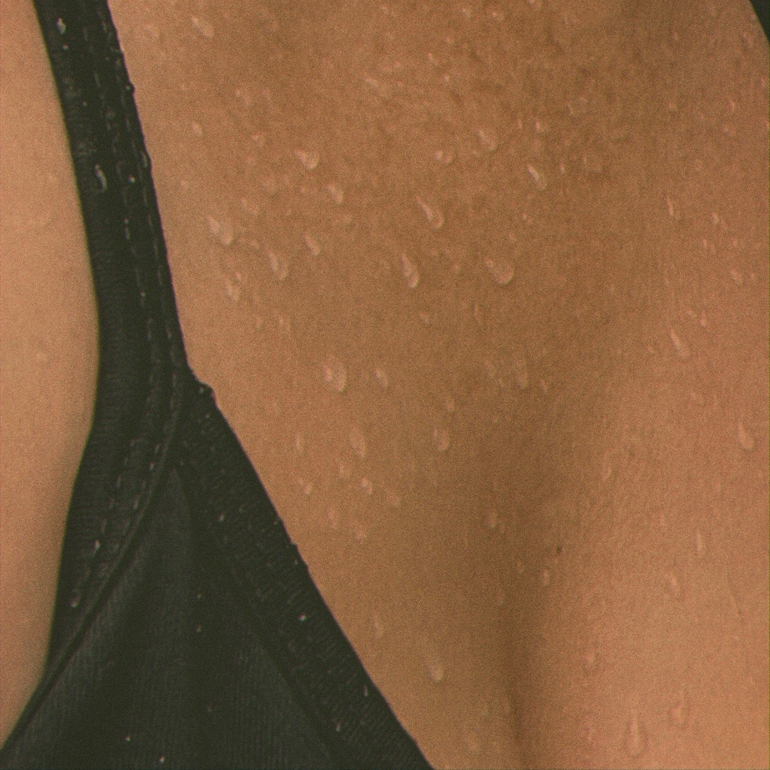 Close-up of a person wearing a black bralette on beige skin.