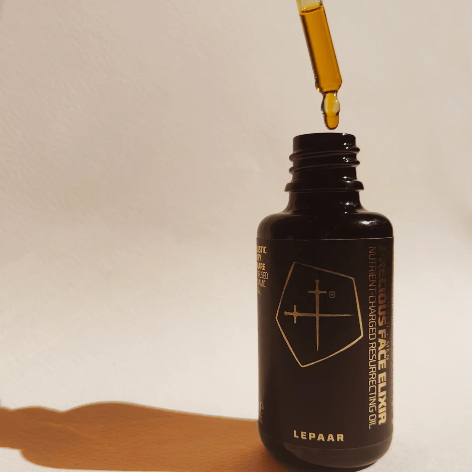 Black bottle of Lepaar Face Elixir with a dropper on a beige background. LEPAAR Precious Face Elixir / Nutrient Charged Resurrecting Oil