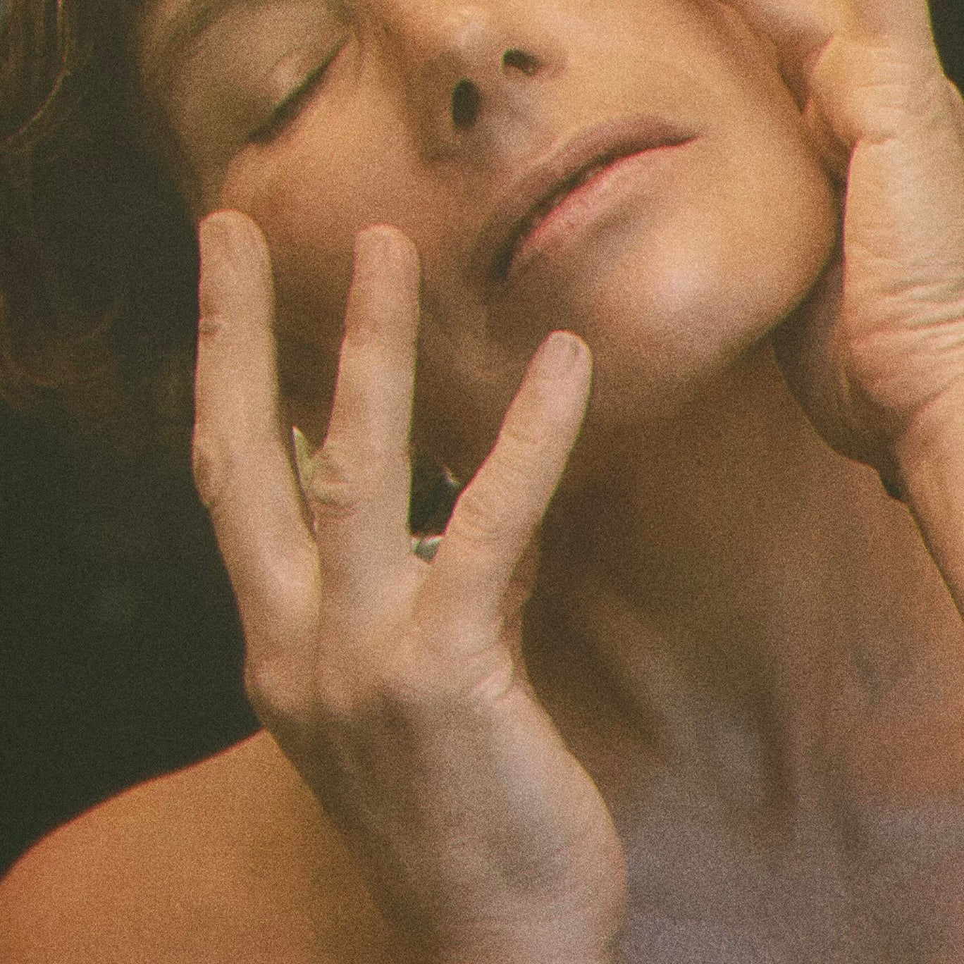 Close-up of a woman's face with hands on her cheeks, against a dark background. LEPAAR Serenity Evening Balsam